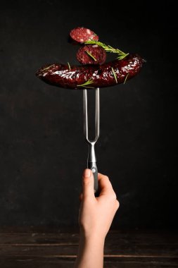 Koyu arka planda lezzetli kanlı sosisli et çatalı.