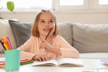 Evde ders çalışan düşünceli küçük kızın portresi.