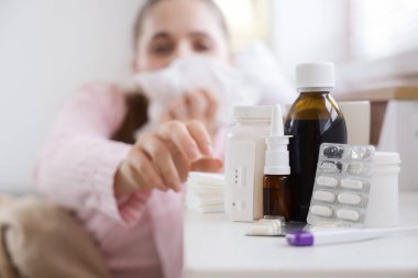 Hasta kadının yatak odasında hapşırmasına karşı farklı grip ilaçları.