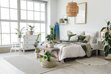 Hafif yatak odasının içinde sörf tahtası, yumuşak bank ve bitkiler var.