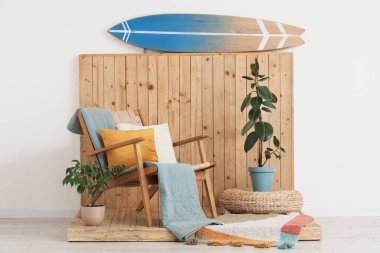 Sörf tahtası, koltuk ve bitkilerle aydınlatma odasının içinde.