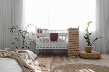 Bebek beşiği ve bitkilerle aydınlık yatak odasının içinde.