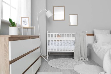 Bebek beşiği, lamba ve boş çerçeveli aydınlık yatak odasının içi