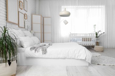 İçinde yatak, bebek beşiği ve katlanır perde olan bir oda.