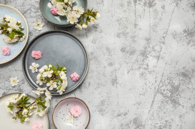 Çiçek açan dalları ve gri arka planda güzel çiçekleri olan farklı temiz tabaklar.
