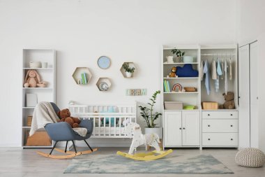 Bebek beşiği, dolabı ve sallanan koltuğu olan bir kreş.