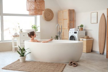 Güzel genç bayan banyoda banyo yapıyor.