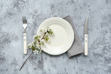 Gri arkaplanda çiçek açan bir dalı olan güzel masa ayarları