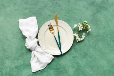 Altın çatal bıçak takımı ve yeşil arka planda çiçek açan dallı güzel bir masa.