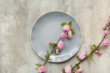 Gri arkaplanda pembe çiçek açan dalları olan güzel masa ayarı