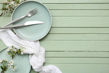 Yeşil ahşap arka planda çiçek açan dalları olan güzel bir masa.