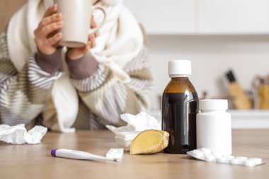 Mutfakta çay içen hasta kadına karşı masasında zencefil olan farklı grip ilaçları.