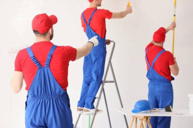 Erkek dekoratörlerden oluşan bir ekip duvarları boyuyor.