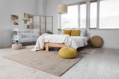 Büyük yataklı, bebek karyolası ve katlanabilir ekranlı bir ışık odası.