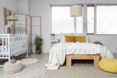 Büyük yataklı, bebek karyolası ve katlanabilir ekranlı bir ışık odası.