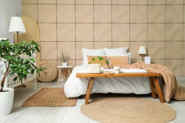 Büyük yataklı, bebek karyolası ve banklı şık bir oda.