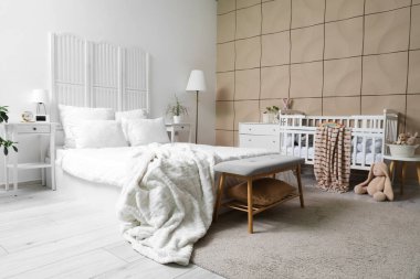 Büyük yataklı, bebek karyolası ve oyuncakları olan şık bir oda.