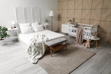 Büyük yataklı, bebek karyolası ve oyuncakları olan şık bir oda.