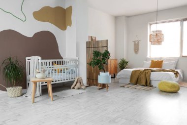 Büyük yataklı, bebek karyolası ve katlanır perdeli şık bir oda.