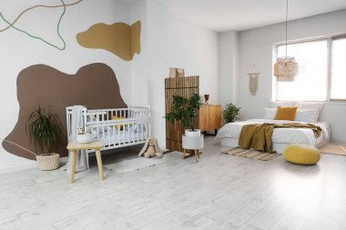 Büyük yataklı, bebek karyolası ve katlanır perdeli şık bir oda.