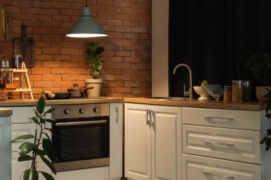 Geceleri tezgah, fırın ve parlayan lamba olan mutfağın içi.