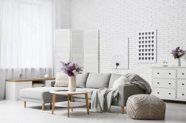 Kanepe, masa ve vazolarda leylak çiçekleri olan oturma odasının içinde.