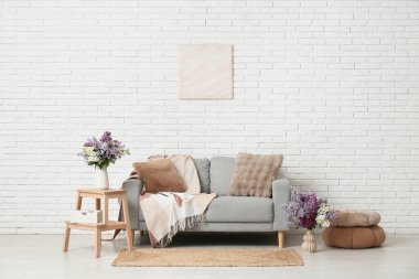 Kanepe, dışkı ve vazolarda leylak çiçekleri olan oturma odasının içinde.