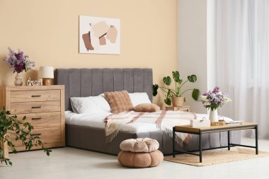 Yatak odasının içinde vazolarda leylak çiçekleri var.