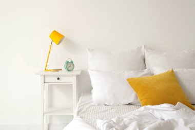 Yatak ve masa üzerinde beyaz çarşaf olan aydınlık odanın içinde.