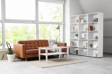 Oturma odasının içinde raf ünitesi, kanepe ve masa var.