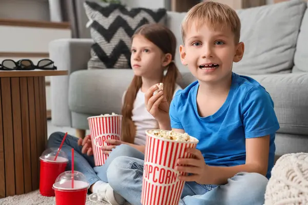 Küçük çocuk ve kız kardeşi evde patlamış mısır izleyip film izliyorlar.