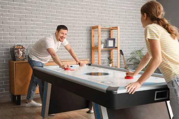 Genç adam ve arkadaşı evde hokey oynuyorlar.