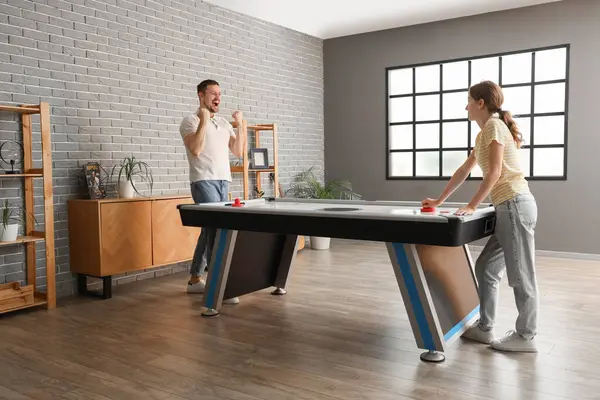 Arkadaşlarıyla evde hokey oynayan mutlu genç bir adam.