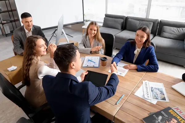 İş adamları konferans odasında el sıkışıyor.