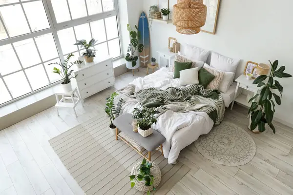 Hafif yatak odasının içinde sörf tahtası, yumuşak bank ve bitkiler var.