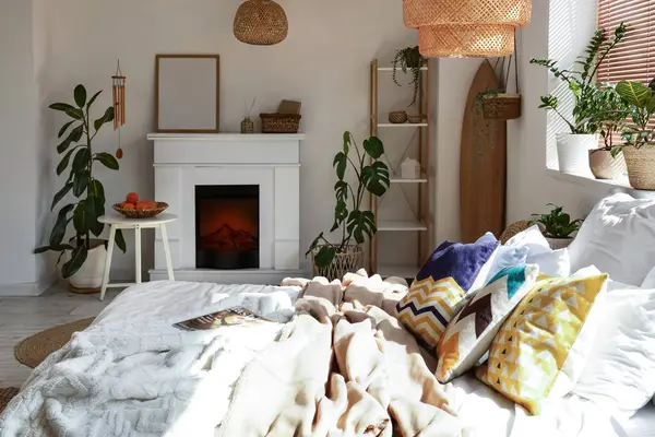 Sörf tahtası, bitkileri ve şöminesi olan aydınlık yatak odasının içi