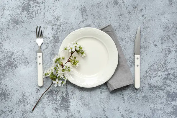 Gri arkaplanda çiçek açan bir dalı olan güzel masa ayarları