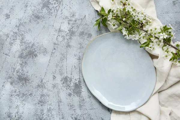 Gri arkaplanda çiçek açan bir dalı olan güzel masa ayarları