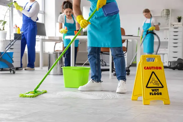 Erkek hademe yerleri paspaslıyor ve ekibi ofisi temizliyor.