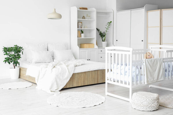 Interior of light room with bed, baby crib and closet