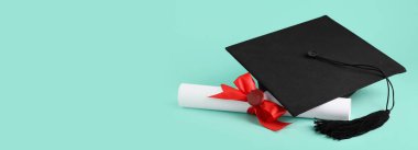 Turkuaz arkaplan üzerine mezuniyet şapkası ve diploması.