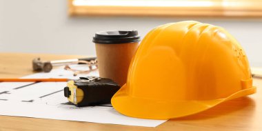 Mezura, kahve fincanı ve ev planı inşaat odasındaki masada, yakın plan.