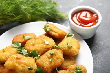 Lezzetli nugget tabağı, ketçap ve siyah masa üzerinde bitkiler.