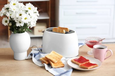 Çıtır ekmek dilimleri ve mutfak masasında tatlı reçelli ekmek kızartma makinesi.