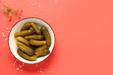 Lezzetli mayalanmış salatalıklı kase ve kırmızı arka planda dereotu.