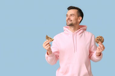 Mavi arka planda lezzetli kurabiyeleri olan yakışıklı bir adam.