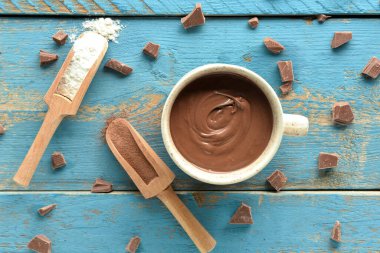 Mavi ahşap arka planda bir fincan lezzetli erimiş çikolata.