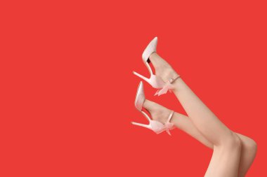 Kırmızı arka planda yüksek topuklu güzel genç bayanların bacakları.