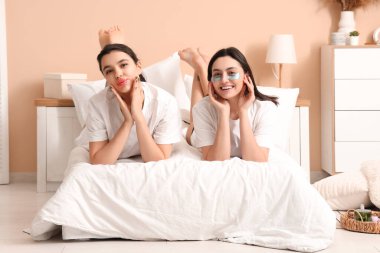 Dudak maskeli ve göz altı bantlı güzel genç kadınlar evde yatıyorlar.