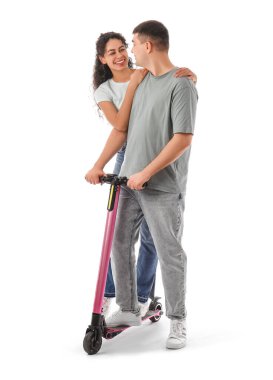 Beyaz arka planda modern elektrikli scooterı olan güzel genç bir çift.